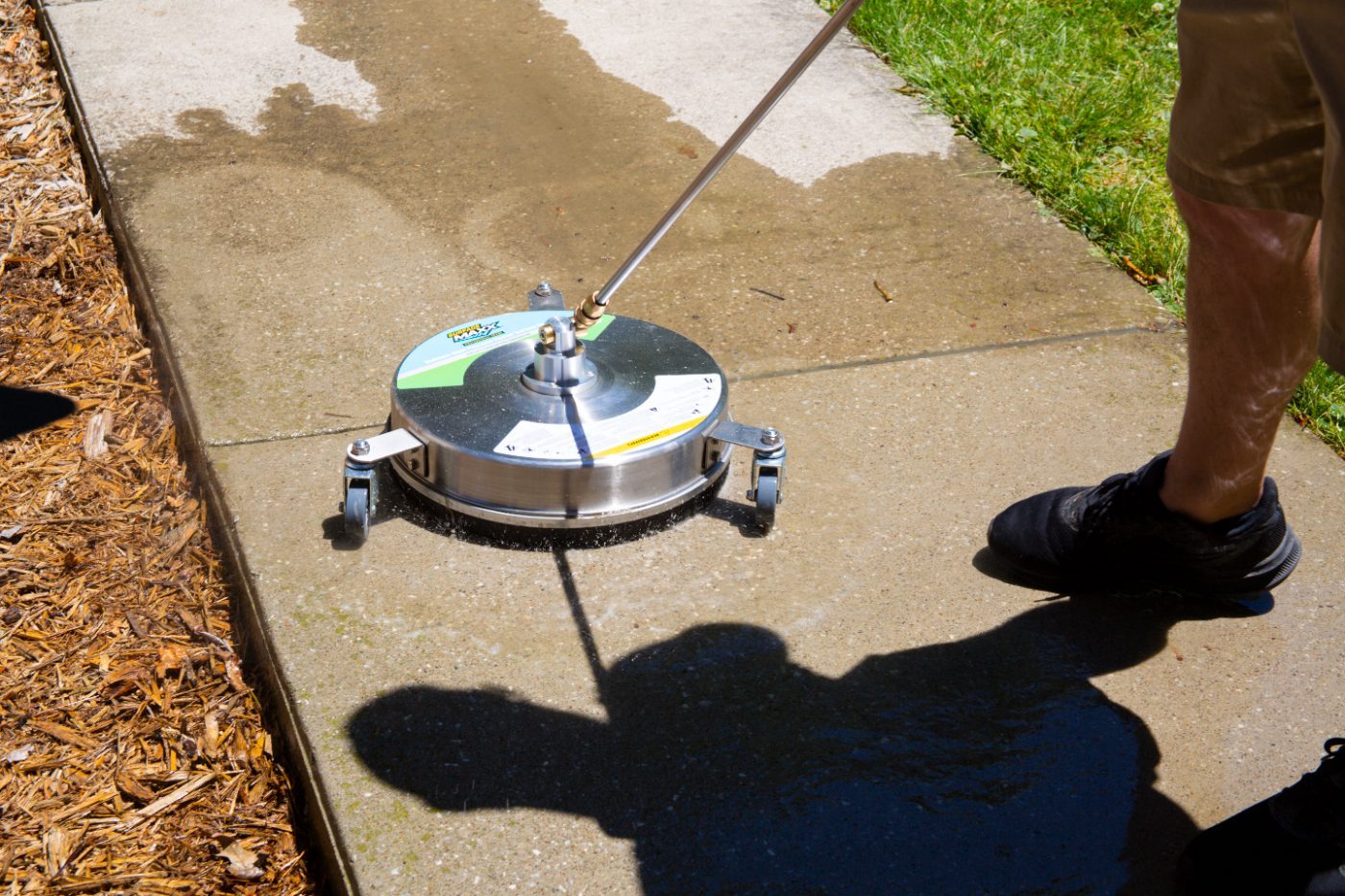A SurfaceMaxx surface cleaner cleaning a dirty concrete sidewalk
